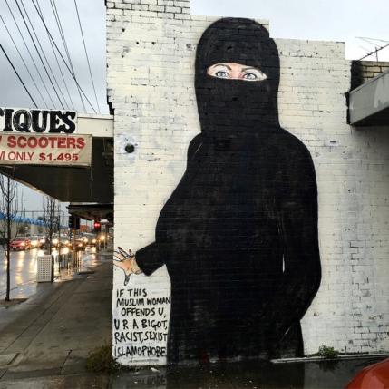 A mural painted by street artist Lushsux, bearing the image of U.S. Democratic Party nominee for President Hillary Clinton wearing islamic dress to cover over the original artwork of a stars-and-stripes themed swimsuit stuffed with cash, is pictured on the wall of a business in the Melbourne suburb of Footscray in Australia, August 1, 2016 in this handout image provided by the artist Lushux REUTERS/Lushsux/Handout via REUTERS ATTENTION EDITORS - THIS IMAGE WAS PROVIDED BY A THIRD PARTY. EDITORIAL USE ONLY NO RESALES. NO ARCHIVE. TPX IMAGES OF THE DAY