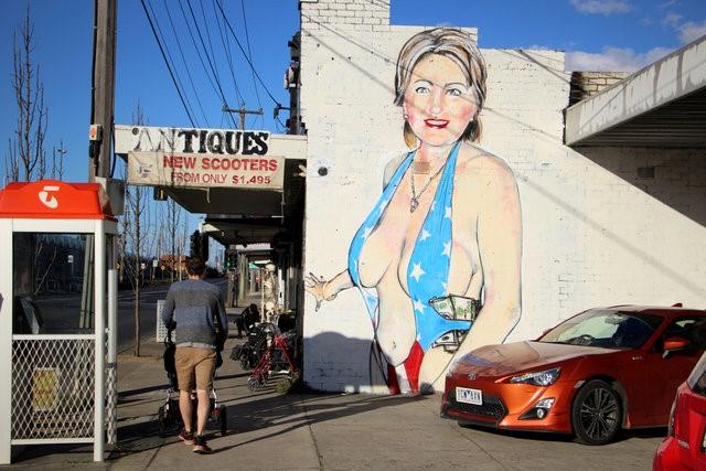 A mural painted by street artist Lushsux, bearing the image of U.S. Democratic Party nominee for President Hillary Clinton wearing a stars-and-stripes themed swimsuit stuffed with cash on the wall of a business in the Melbourne suburb of Footscray, Australia, July 31, 2016. REUTERS/Jarni Blakkarly