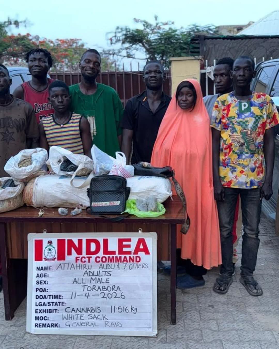Group of people standing behind a table covered with bagged substances and a sign reading INDLEA FCT COMMAND, suggesting a cannabis seizure display.