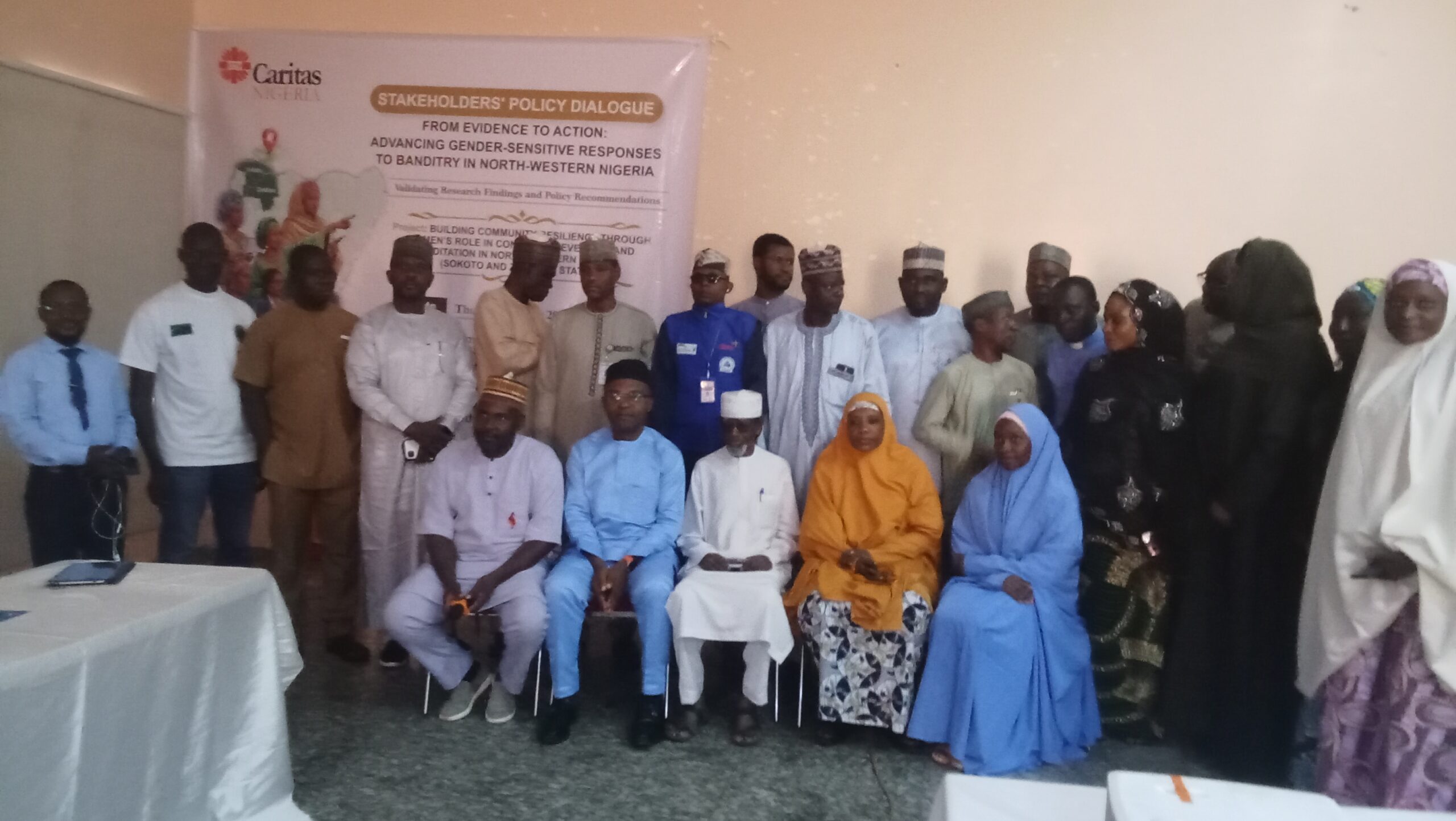 Group of people in traditional attire posing for a photo at a stakeholder policy dialogue event.