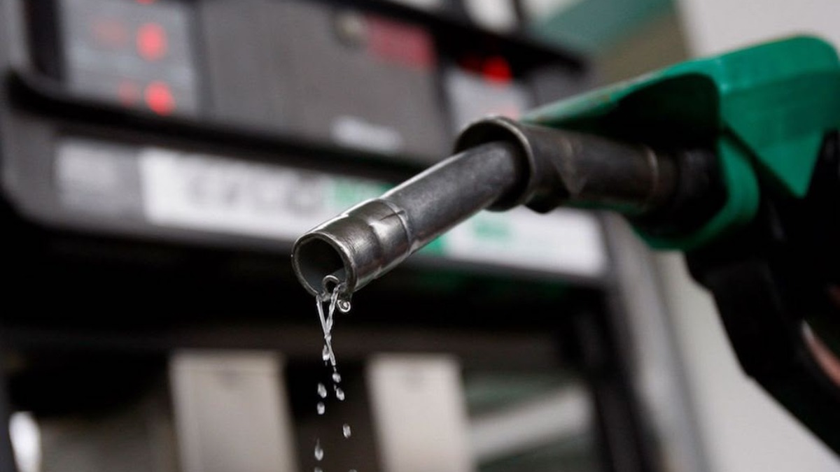 Close-up of a green gas pump nozzle with liquid dripping from the spout.
