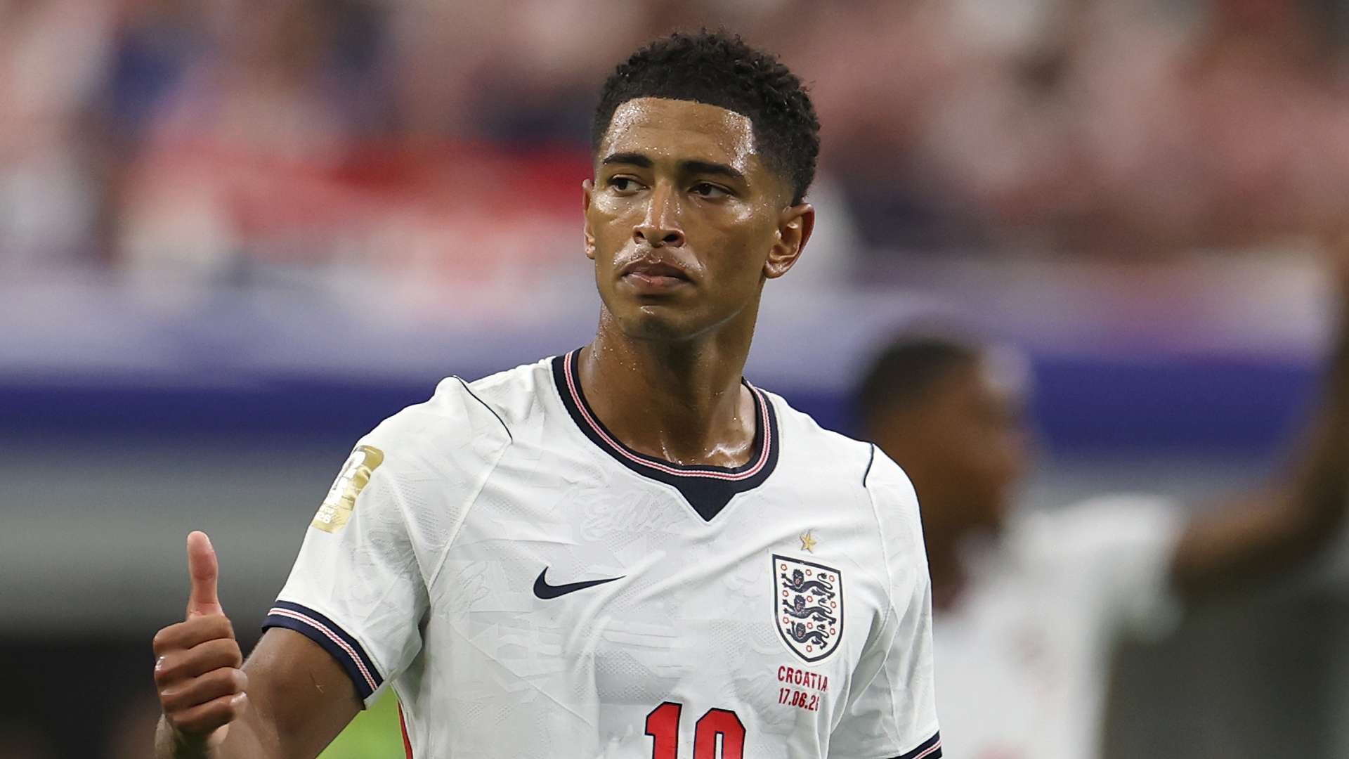 Jude Bellingham - THEWILL NEWS MEDIA England footballer in a white jersey giving a thumbs up on the pitch and looking to the side.