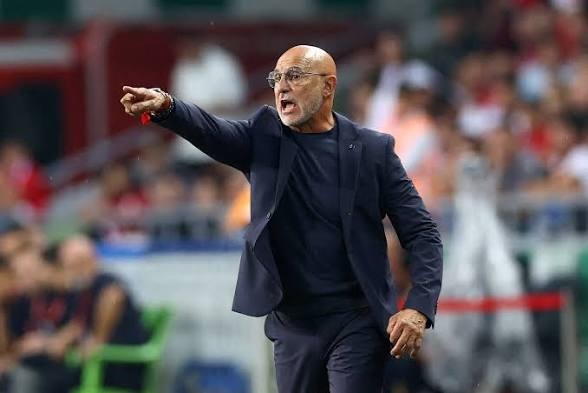 Spain head coach Luis de la Fuente celebrates after masterminding a tactical masterclass that sent La Roja into the 2026 FIFA World Cup final. - THEWILL NEWS MEDIA Bald man in a dark suit gesturing with his arm extended on the sideline during a sports match, crowd blurred in background.