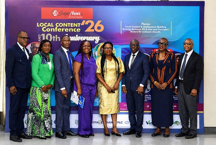 Nigeria Local Content Confab 2026 and the organisation's 10th Anniversary celebration held in Lagos - THEWILL NEWS MEDIA Group of eight professionals in formal attire posing for a photo at the Local Content Conference ’26 anniversary backdrop with event banners and logos.
