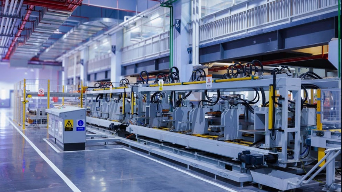 A representation of manufacturing plant - THEWILL NEWS MEDIA Industrial manufacturing plant with large automated machinery and overhead piping lining a spacious factory floor.