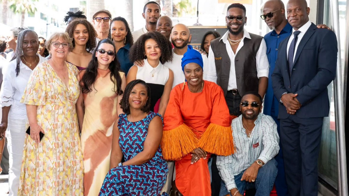 Angélique Kidjo - THEWILL NEWS MEDIA A diverse group of smiling people posing for a group photo at a social event, indoors/outdoors setting visible in the background.