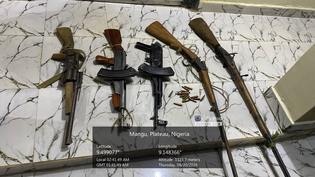 Army Recovers Ammunition - THEWILL NEWS MEDIA Five rifles with wooden stocks and scattered cartridges laid on a marble floor, with a location overlay reading Mangu, Plateau, Nigeria and GPS coordinates nearby in the frame.