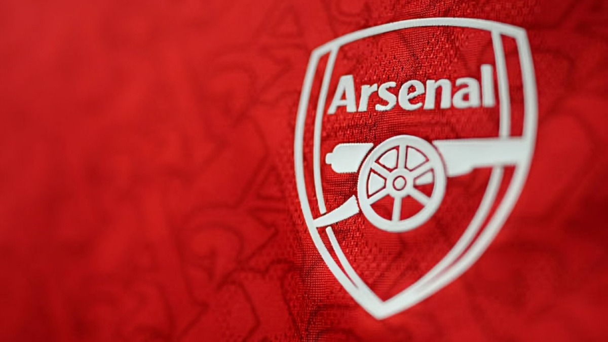 Arsenal - THEWILL NEWS MEDIA Arsenal football club crest on red fabric background with a white cannon emblem
