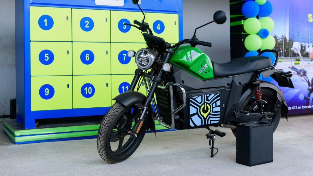 Battery Swap - THEWILL NEWS MEDIA Green and black motorcycle on display beside lime-yellow lockers with blue numbers in an indoor showroom.