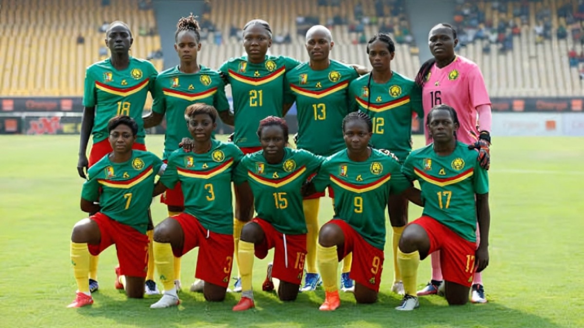Cameroon girls - THEWILL NEWS MEDIA Cameroon women's national football team posing for a group photo on the stadium field, green jerseys with red shorts and yellow socks, goalkeeper in pink on the right.