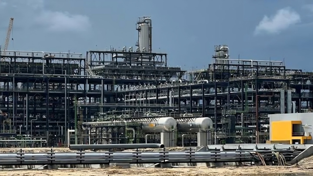 Dangote Refinery - THEWILL NEWS MEDIA Extensive refinery with interconnected pipes and metal structures under a blue sky.