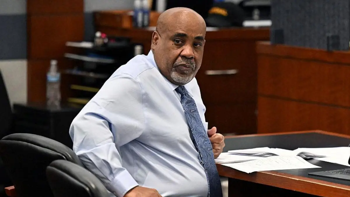 Duane Keffe D Davis - THEWILL NEWS MEDIA Middle-aged man in a light blue shirt and patterned tie sits at a desk with scattered papers in a courtroom or office setup.