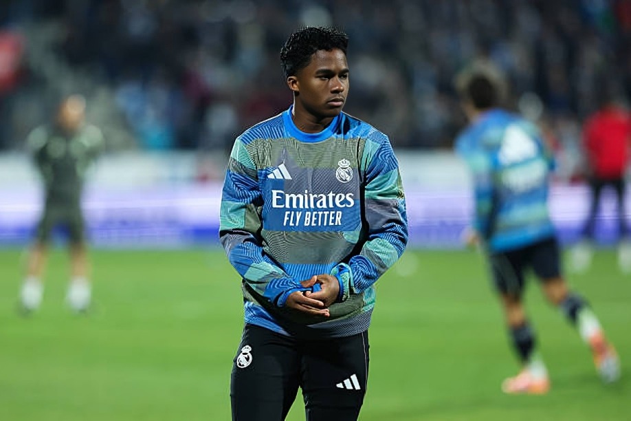 Endrick - THEWILL NEWS MEDIA Soccer player in a blue Real Madrid training jersey standing on a green field, hands clasped in front.