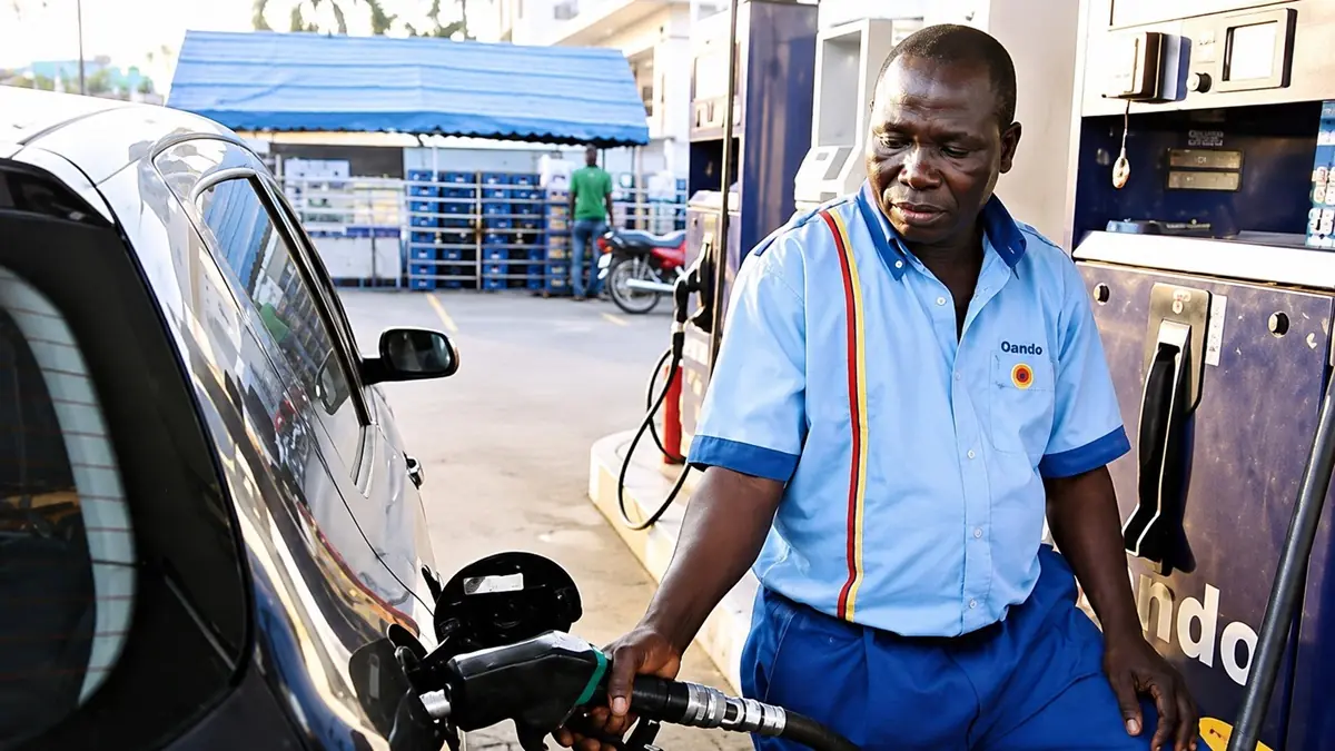 Fuel attendant- OANDO - THEWILL NEWS MEDIA Gas station attendant in a blue uniform refueling a silver car at a pump.