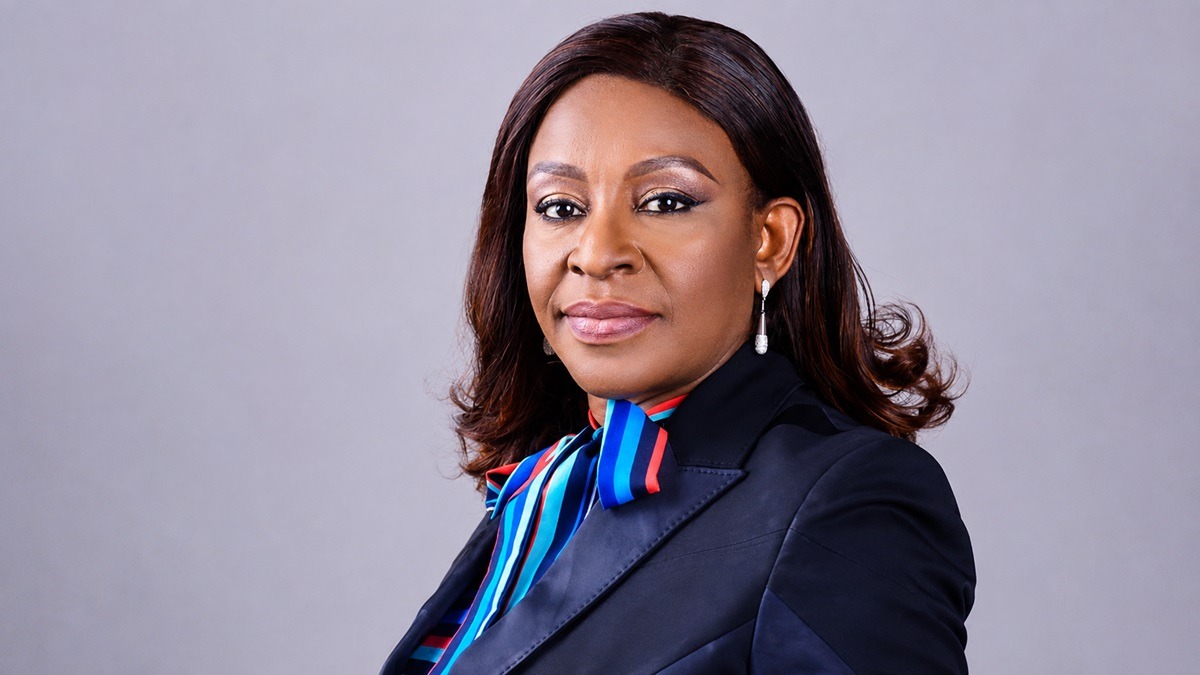 Nonye Ayeni - THEWILL NEWS MEDIA Professional woman in a navy blazer with a striped blue and red scarf, facing the camera.