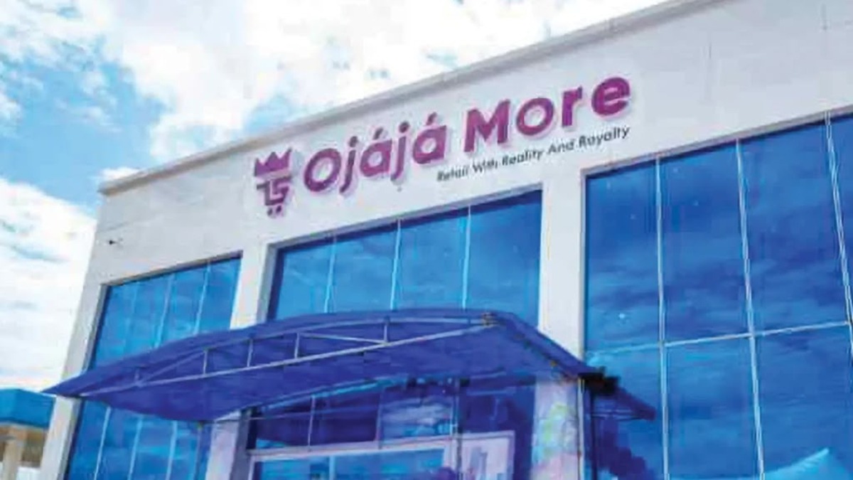 Ojaja More - THEWILL NEWS MEDIA Exterior view of a modern storefront with large blue-tinted glass windows and a purple sign that reads 'Ojaja More' above the entrance, with a blue canopy over the door