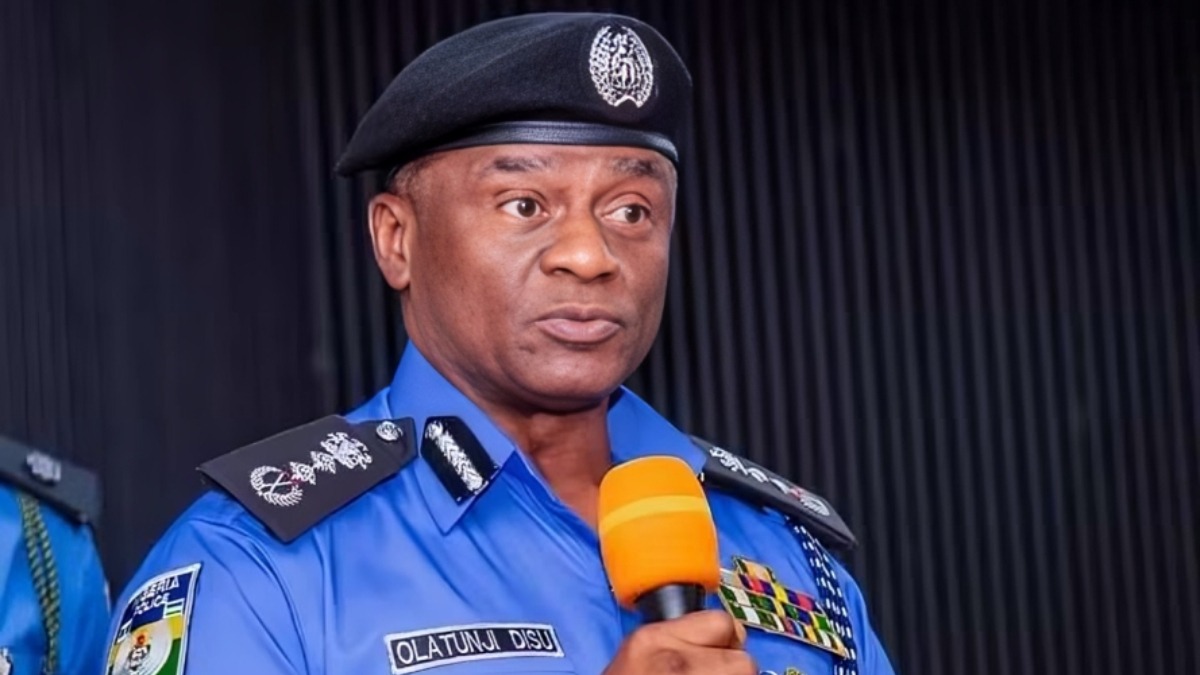 Olatunji Disu 1 - THEWILL NEWS MEDIA Nigerian police officer in a blue uniform holding an orange microphone and speaking. The name tag reads'OLATUNJI DISU'.
