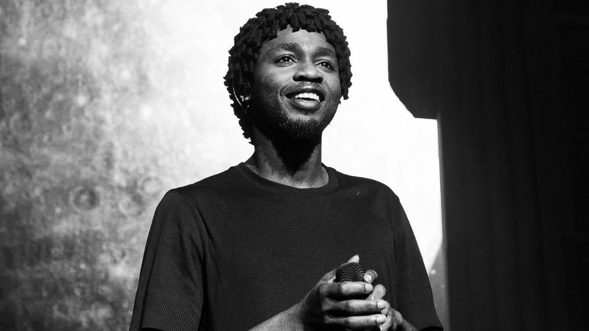 Omah Lay - THEWILL NEWS MEDIA Male performer on stage, smiling while holding a microphone in a black-and-white photo.