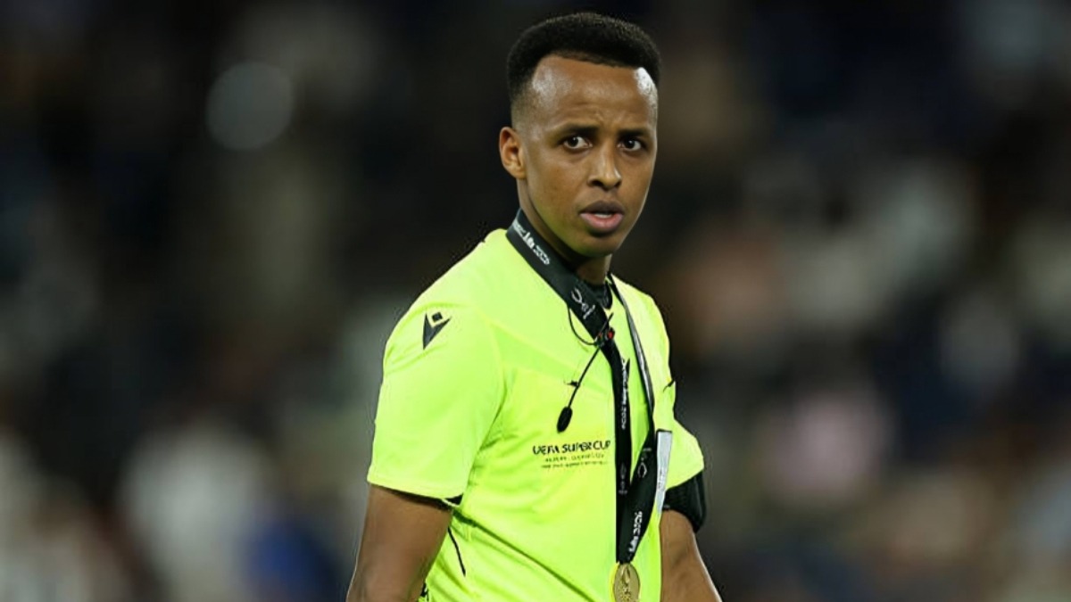 Omar Abdulkadir Artan - THEWILL NEWS MEDIA Sports official in a neon yellow jersey with a lanyard and medal at a stadium.