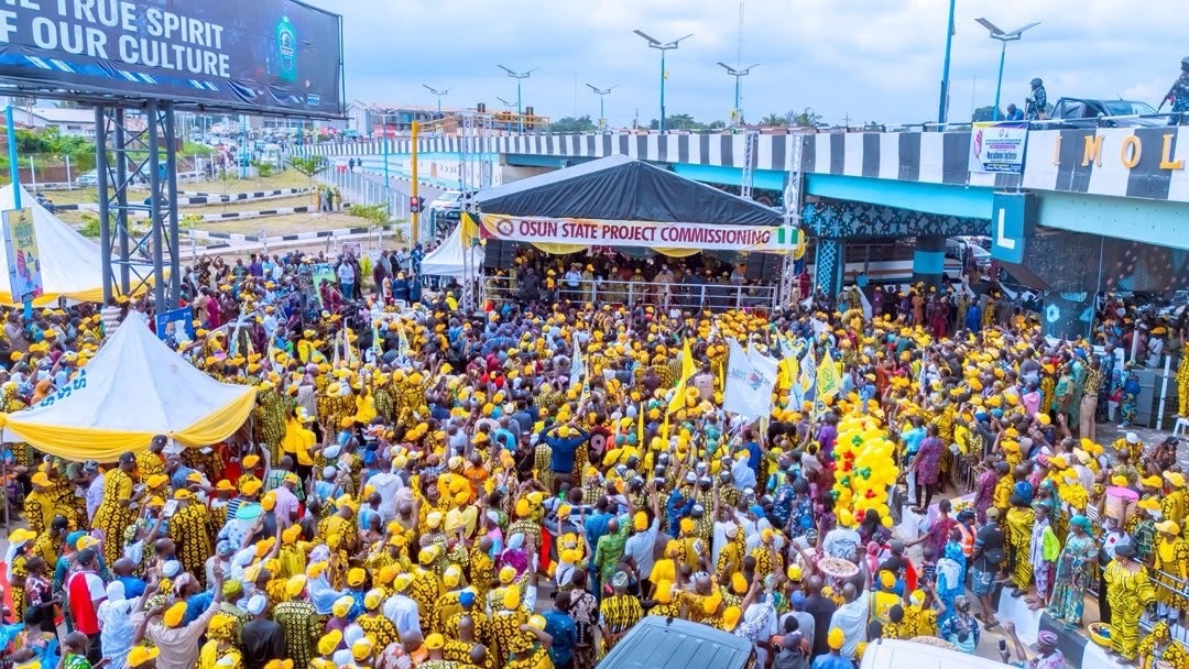 Osun state 1 - THEWILL NEWS MEDIA Large crowd of people in yellow outfits gathered at an Osun State project commissioning ceremony with a stage tent visible ahead.