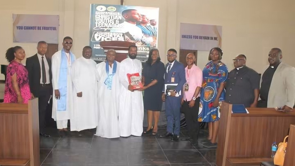 Participants pose for a group photograph after the Organisation of African Instituted Churches OAIC - THEWILL NEWS MEDIA Group of people posing in a church hall, clergy in white robes center, someone holding a red book, others in formal attire.