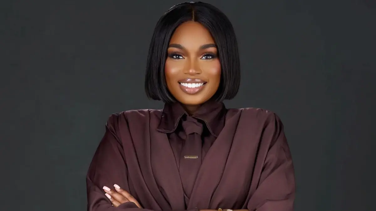 Sabrina Idukpaye - THEWILL NEWS MEDIA Portrait of a smiling woman with a sleek bob haircut, wearing a burgundy blouse, arms crossed against a dark studio backdrop.