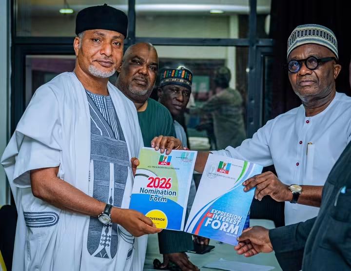 Senator Saliu Mustapha 2 - THEWILL NEWS MEDIA Four men in traditional Nigerian attire hold up 2026 nomination and expression of interest forms at a political event.