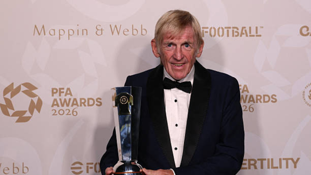 Sir Kenny Dalglish - THEWILL NEWS MEDIA Older man in a tuxedo holding a tall trophy at the PFA Awards 2026 event, smiling for the camera.