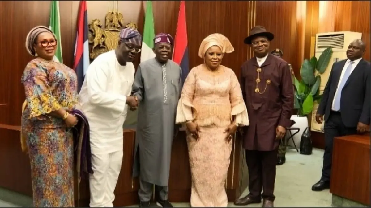 Tinubu swear in Abel Enitan - THEWILL NEWS MEDIA Group of six adults in formal Nigerian attire posing for a photo in a wood-paneled room with flags in the background.