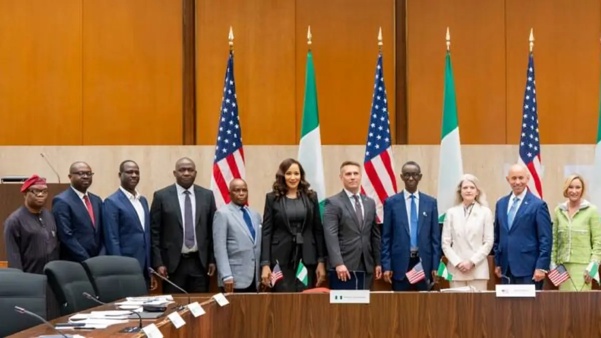 US Nigeria Deepen Security Cooperation - THEWILL NEWS MEDIA Diverse group of officials posing for a photo in a conference room with US and Nigerian flags in the background.