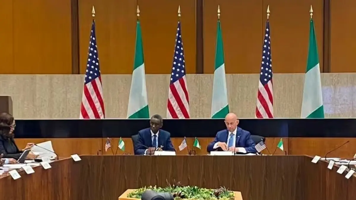 US Nigeria Deepen Security Cooperation - THEWILL NEWS MEDIA Delegates at a long conference table signing documents, with alternating U.S. and Irish flags in the background.