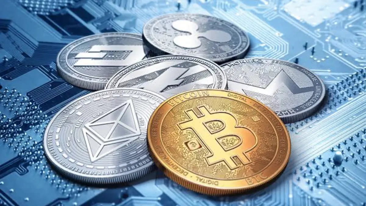 virtual assets - Crypto 1 - THEWILL NEWS MEDIA Gold Bitcoin coin in the foreground with silver Ethereum and other crypto coins on a blue circuit-board background, symbolizing digital currency
