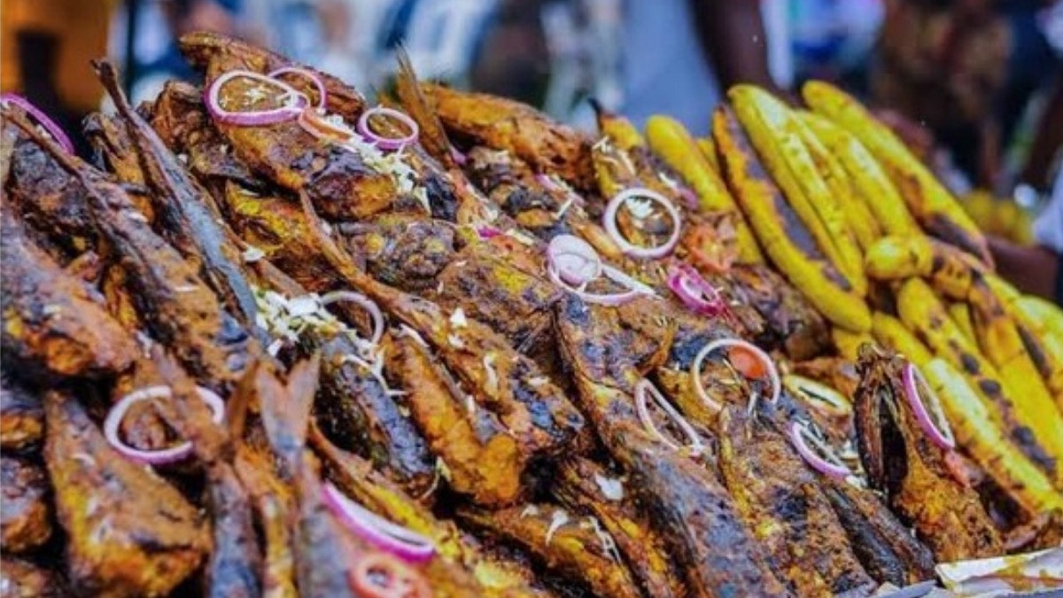 Bòlé Festival - THEWILL NEWS MEDIA Pile of fried fish stacked on a market stall, garnished with onion rings and spices.