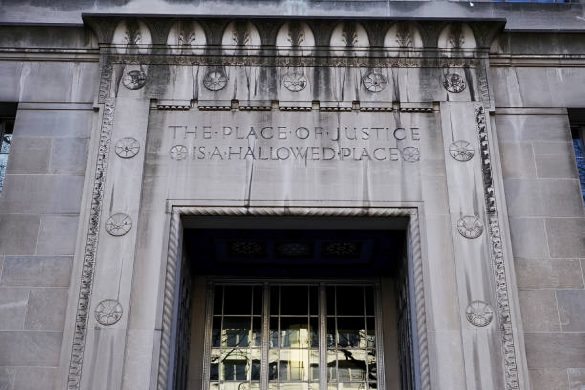 Department of Justice headquarters in Washington DC - THEWILL NEWS MEDIA Stone courthouse entrance with carved inscription:'The place of justice is a hallowed place' above a metal-framed doorway.
