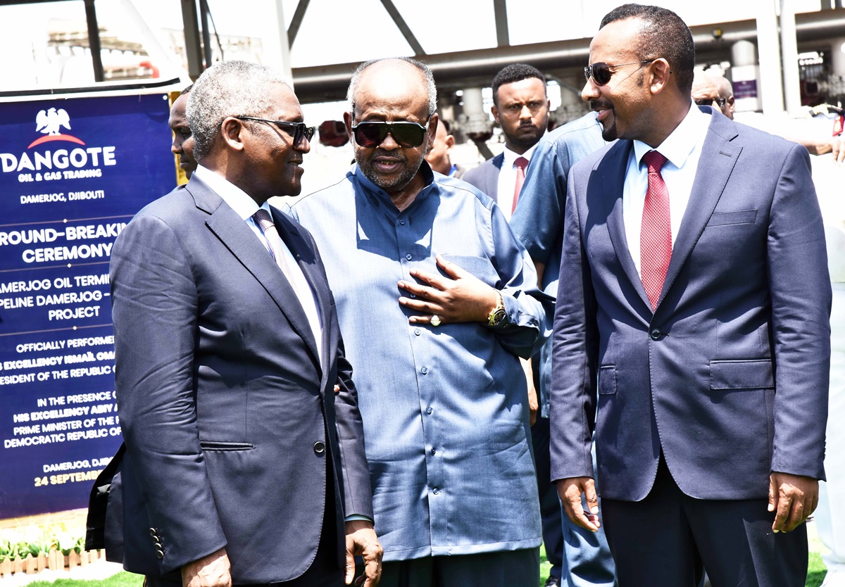 Ethiopia Djibouti leaders back Dangote Oil and Gas - THEWILL NEWS MEDIA Three men in suits chat at a Dangote oil project ground-breaking ceremony, with a large blue event sign in the background.