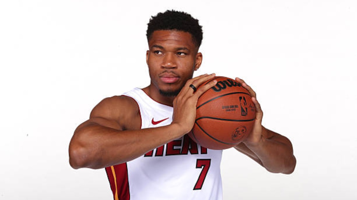 Giannis Antetokounmpo Miami Heat - THEWILL NEWS MEDIA Basketball player in a white sleeveless jersey holding a basketball in front of the chest, preparing to pass.