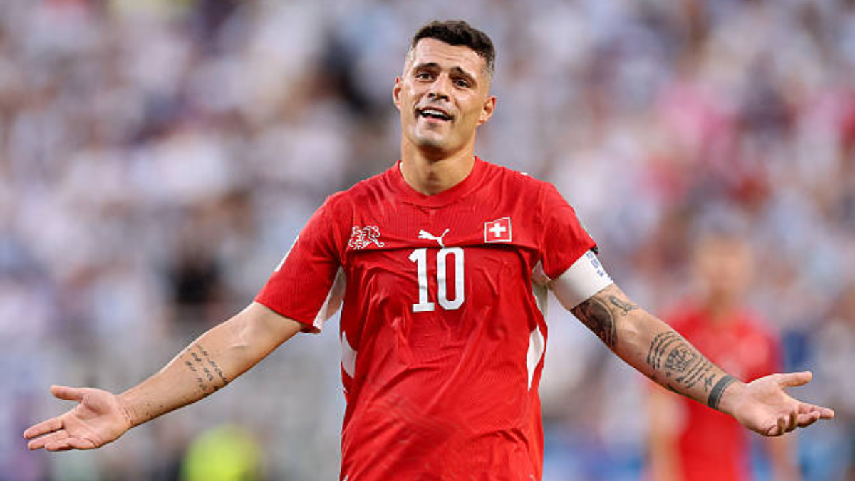 Granit Xhaka - THEWILL NEWS MEDIA Soccer player in a red Switzerland jersey with number 10, arms outstretched in celebration on the field.
