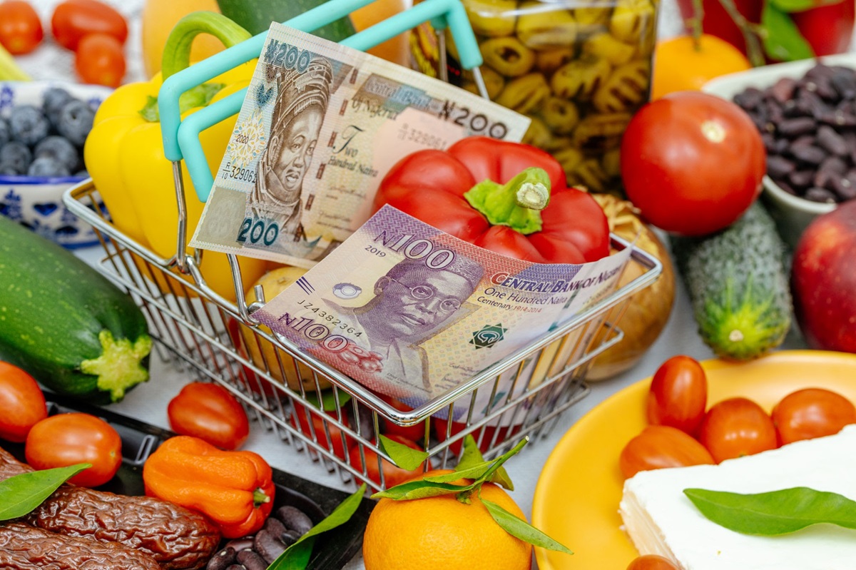 Market food basket - THEWILL NEWS MEDIA A shopping cart filled with fresh produce, with Nigerian naira notes tucked among peppers and vegetables, implying grocery budgeting.