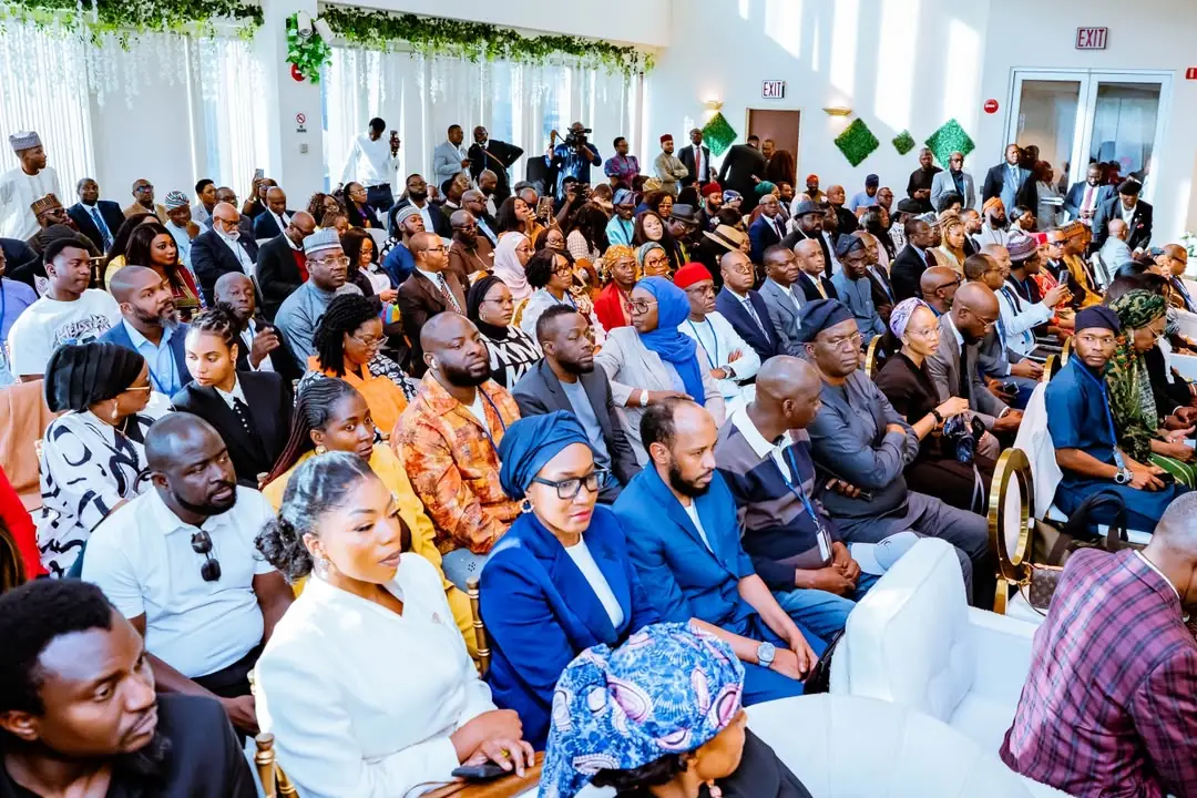 Large diverse audience seated in a bright hall during a formal event or conference.