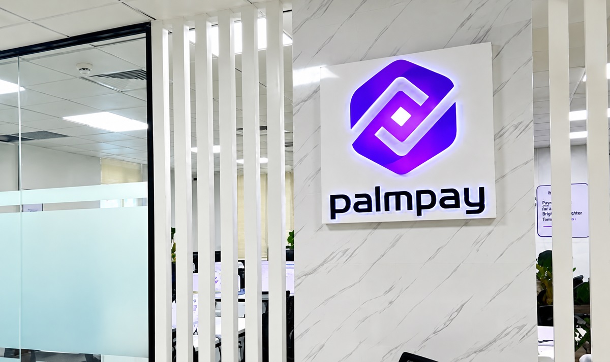PalmPay - THEWILL NEWS MEDIA Palmpay logo on white marble wall inside a modern office lobby/ reception area into light and glass partitions nearby.