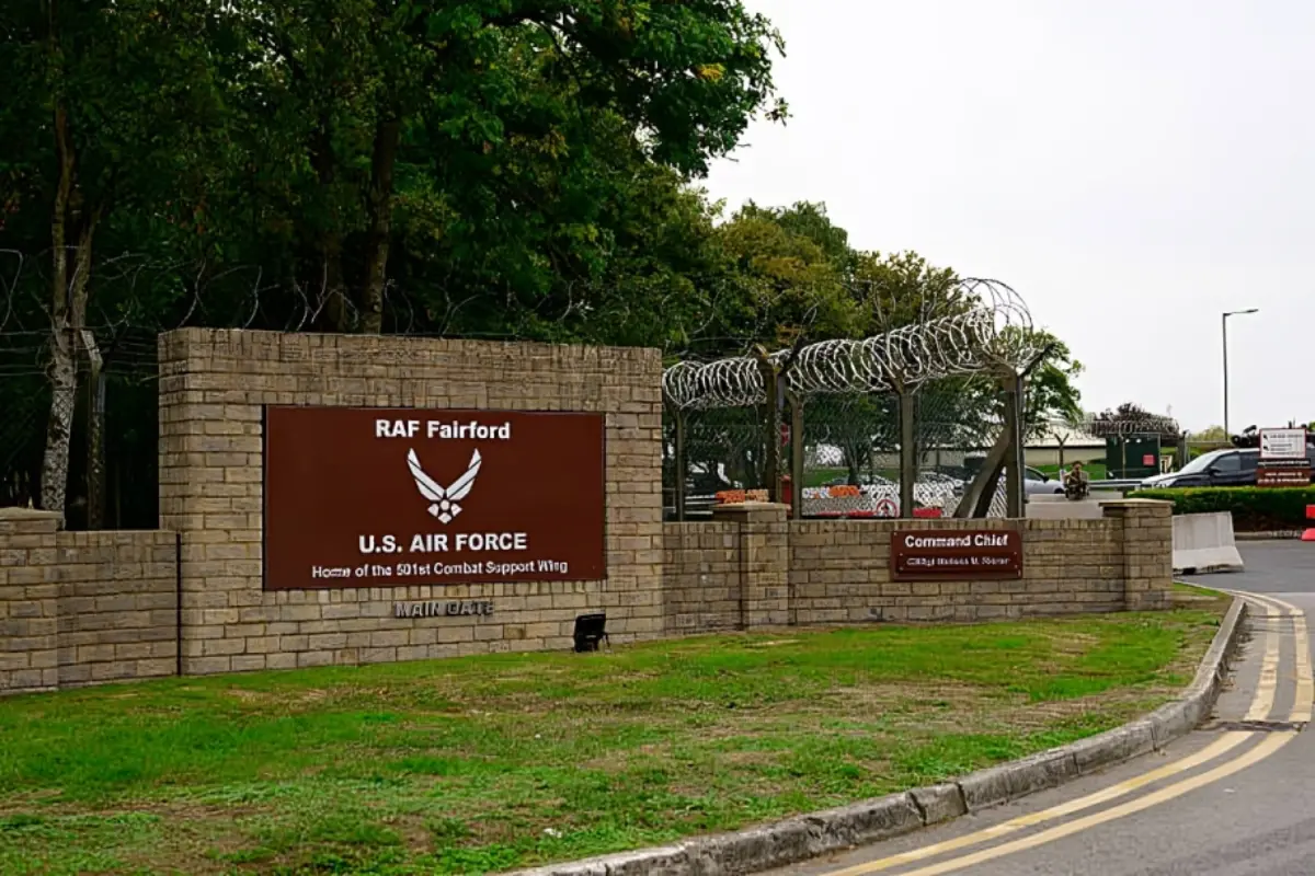 RAF Fairfor Us Air Force in Uk - THEWILL NEWS MEDIA Entrance sign for RAF Fairford U.S. Air Force base with a stone wall and barbed-wire fence nearby.
