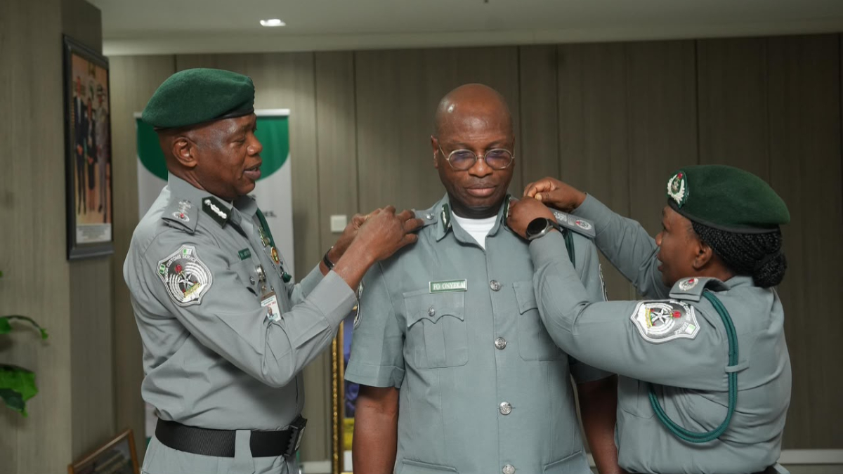 Representation of New appointments - THEWILL NEWS MEDIA Two uniformed officers pin decorations on a colleague in a formal award ceremony.
