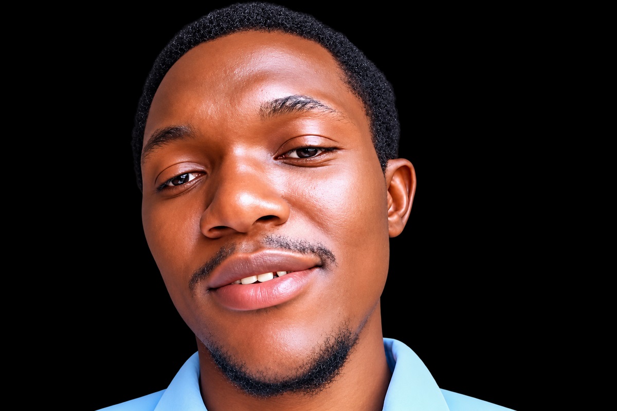 Abdussamad Ohida - THEWILL NEWS MEDIA Close-up portrait of a smiling man with short hair and a light blue shirt against a black background.