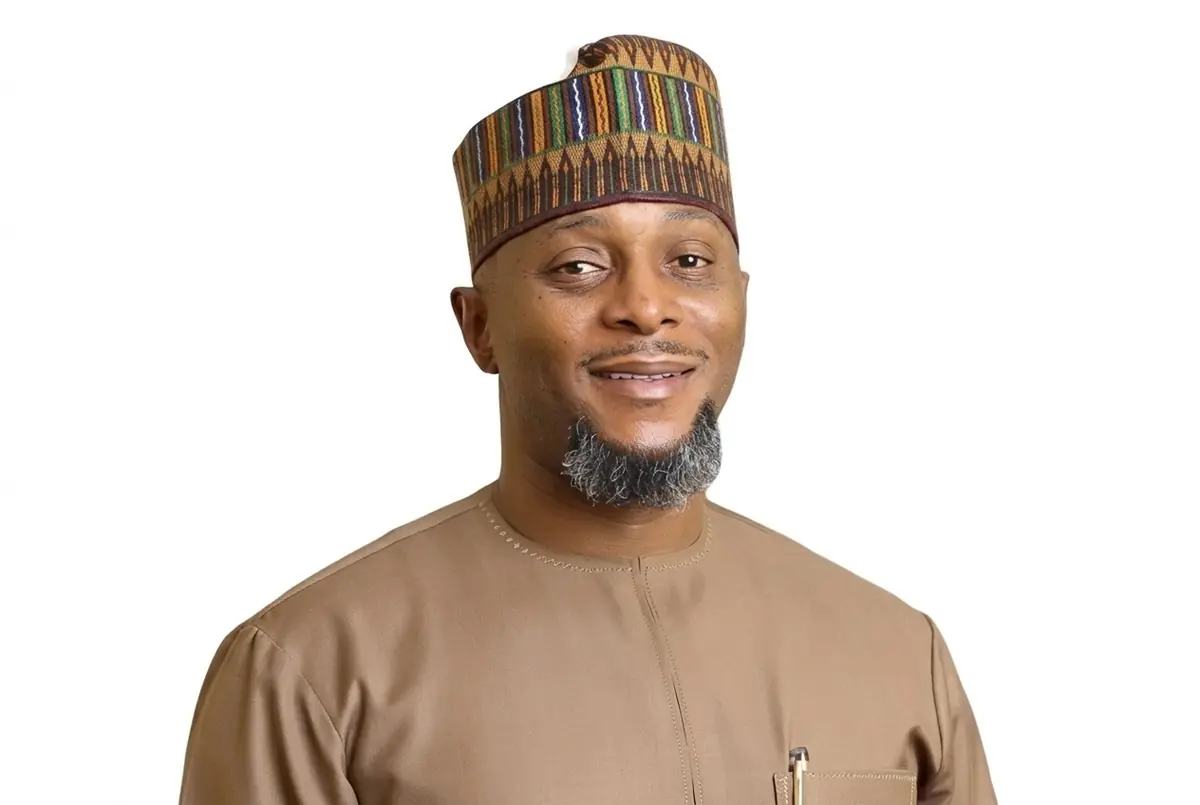 Adamu Atiku Abubakar - THEWILL NEWS MEDIA Man in a brown traditional outfit and a patterned cap, smiling at the camera against a white background.