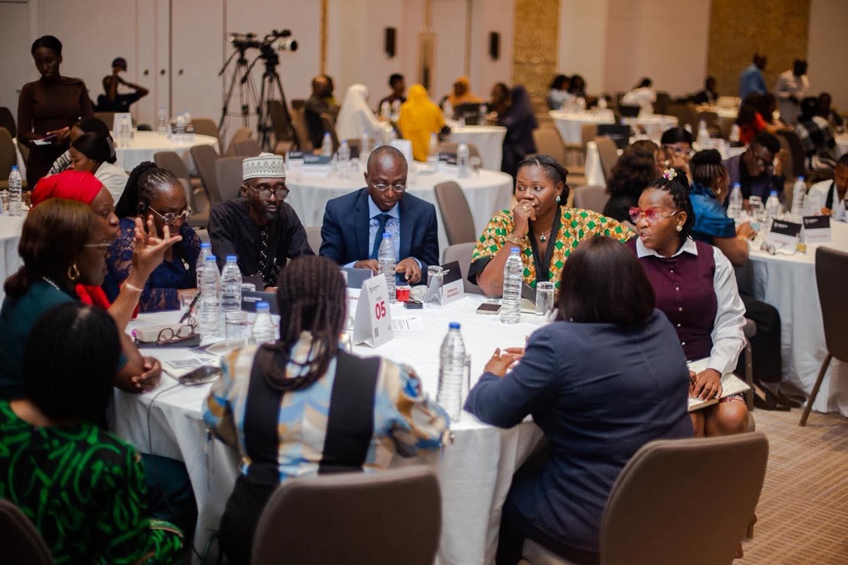 Aig-Imoukhuede Foundation - THEWILL NEWS MEDIA Group of diverse professionals seated around a round table at a conference, discussing with bottles of water and documents on the table.
