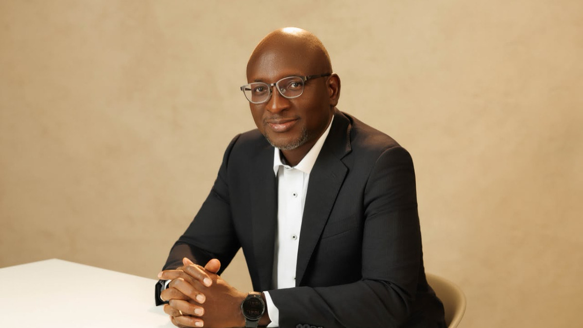 Akeem Lawal - THEWILL NEWS MEDIA Professional man in a dark suit and white shirt seated at a table, looking at the camera with hands folded in front of him.
