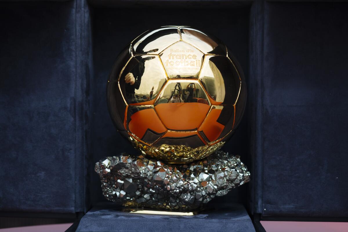 Golden Ballon d'Or trophy on a sparkling crystal base inside a dark display case