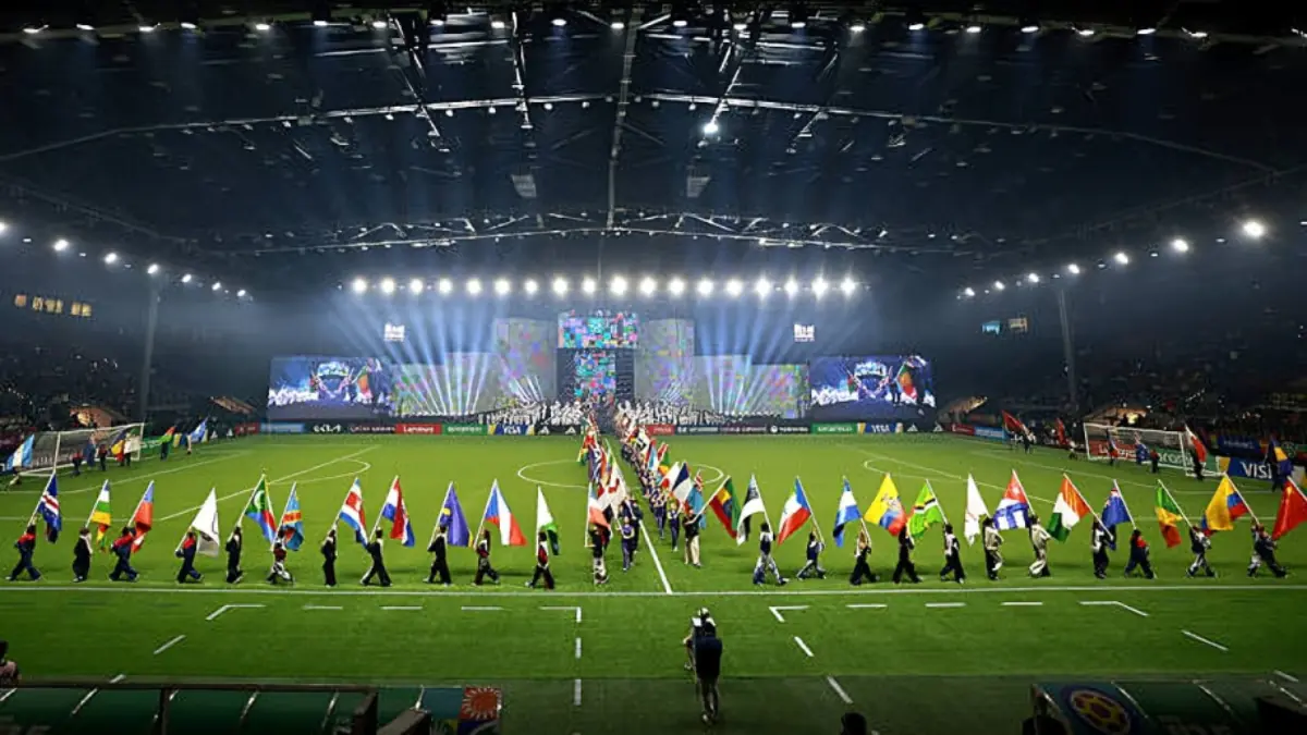 FIFA U15 World Cup Festival - THEWILL NEWS MEDIA Flag bearers march along a lit stadium field toward a large, colorful stage during a night opening ceremony.