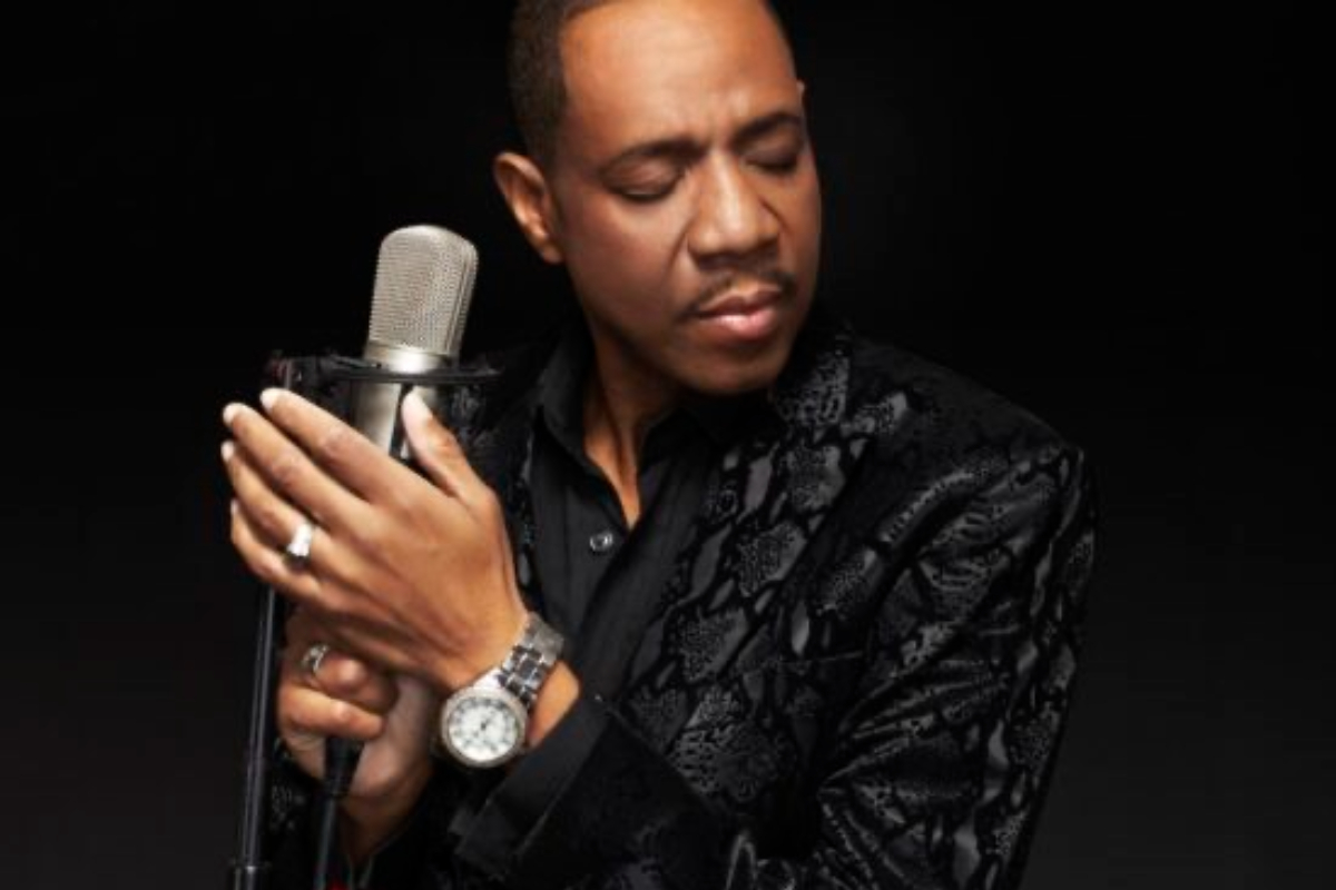 Freddie Jackson - THEWILL NEWS MEDIA Male singer in a black patterned jacket holds a microphone with eyes closed, performing.