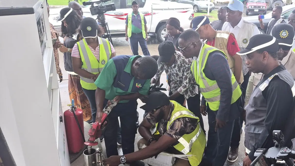 Fuel testing - THEWILL NEWS MEDIA Group of workers at a fueling station watching a safety procedure demonstration around a fuel pump and fire extinguisher on site.
